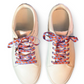 Pair of beige sneakers with colorful and fun lobster shoelaces on a white background