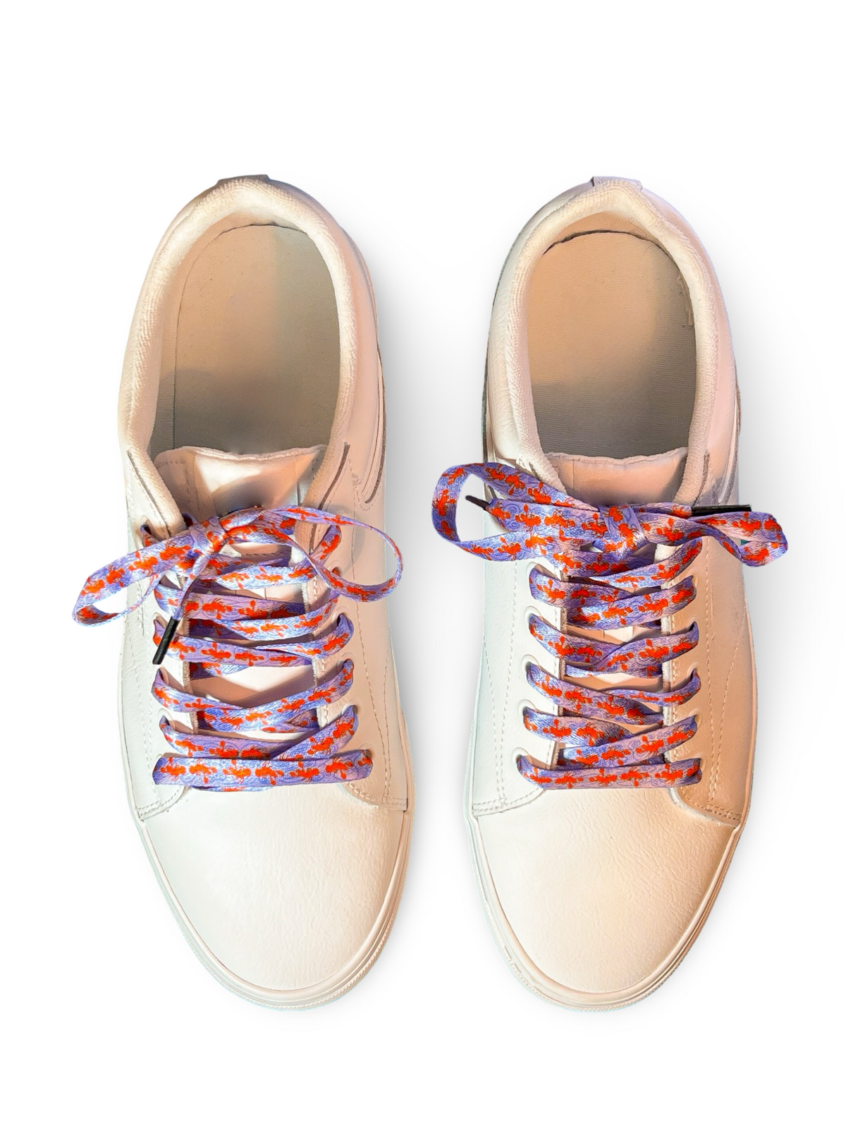 Pair of beige sneakers with colorful and fun lobster shoelaces on a white background