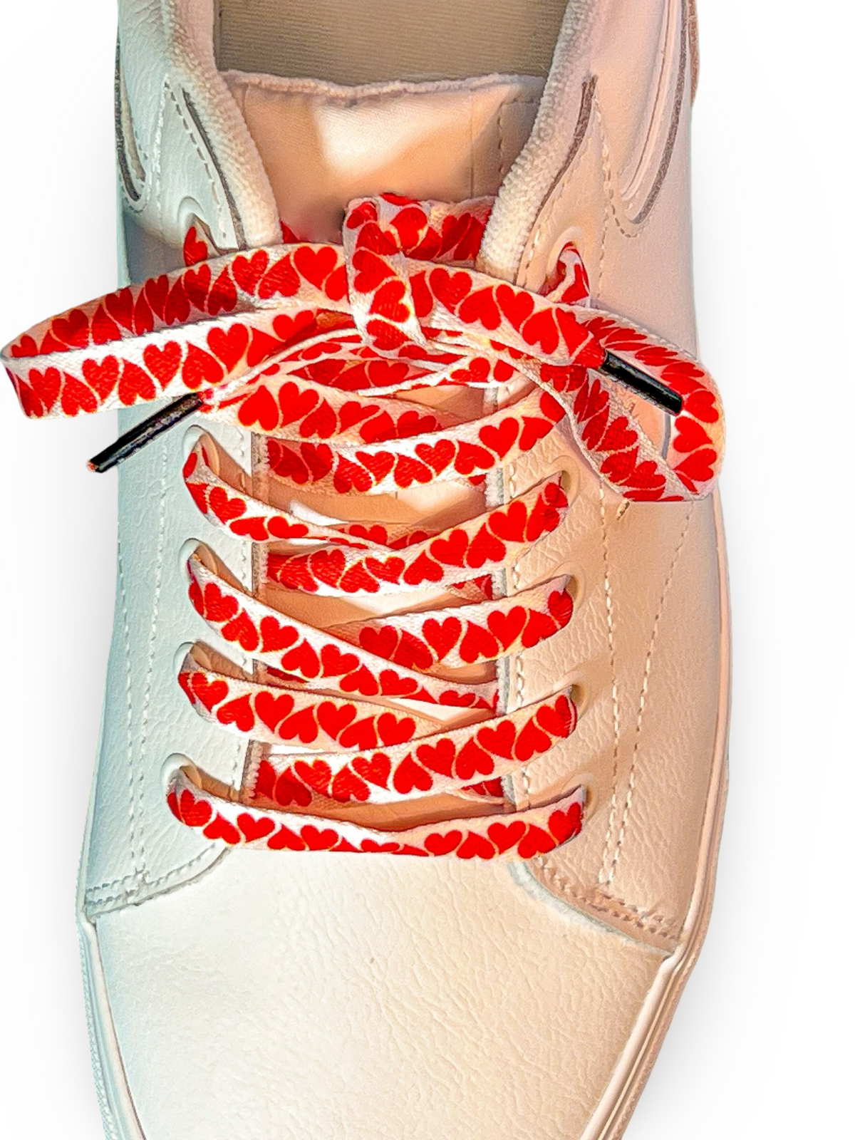 White sneaker with red heart-patterned shoelaces on a white background