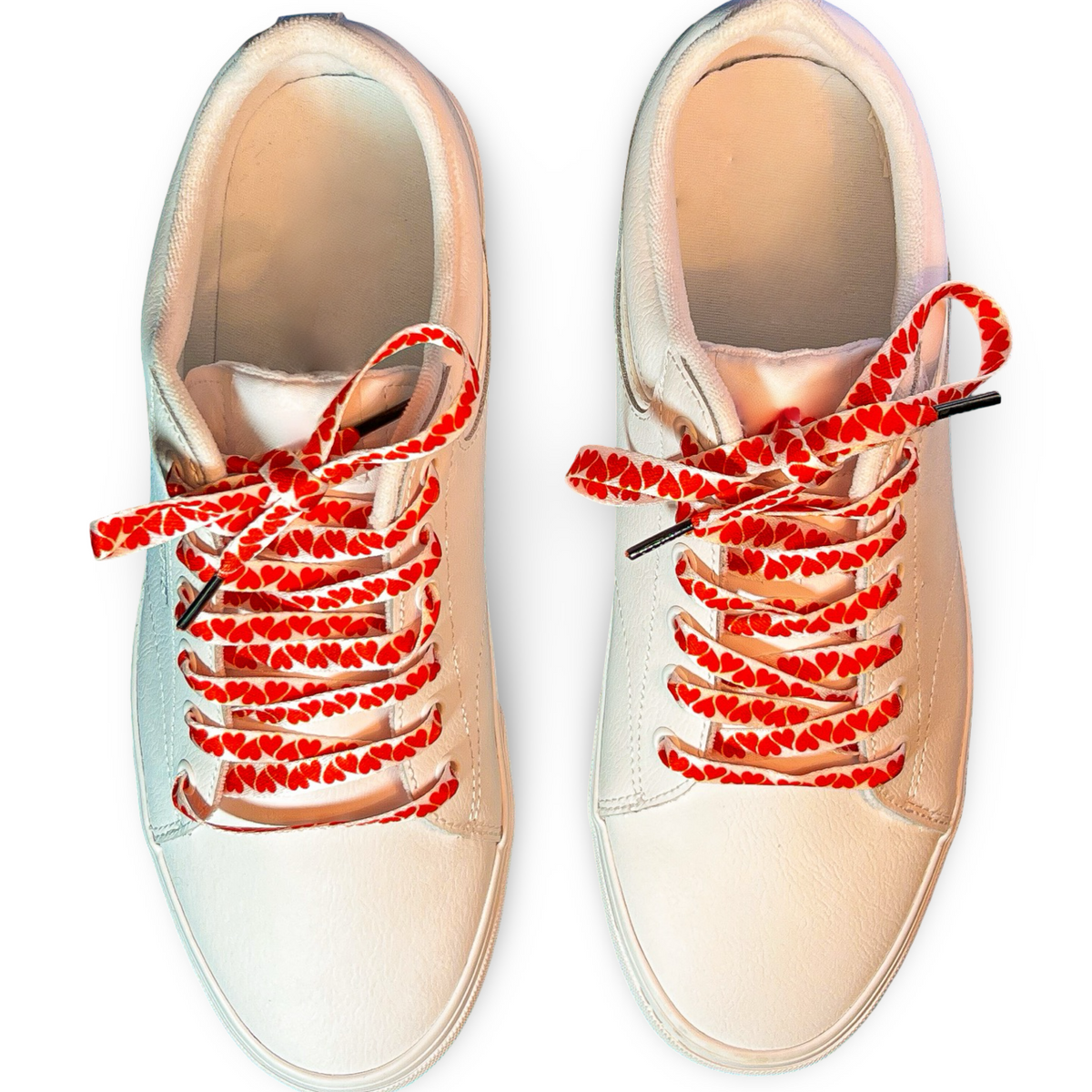 Beige sneakers with colorful heart shoelaces on a white background