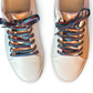 Pair of beige sneakers with colorful zigzag laces on a white background