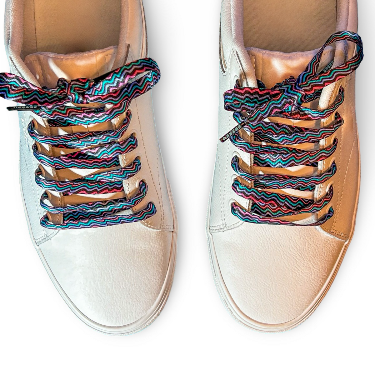 Pair of beige sneakers with colorful zigzag laces on a white background