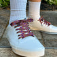 white sneakers with colorful laces worn with white socks on a concrete surface.