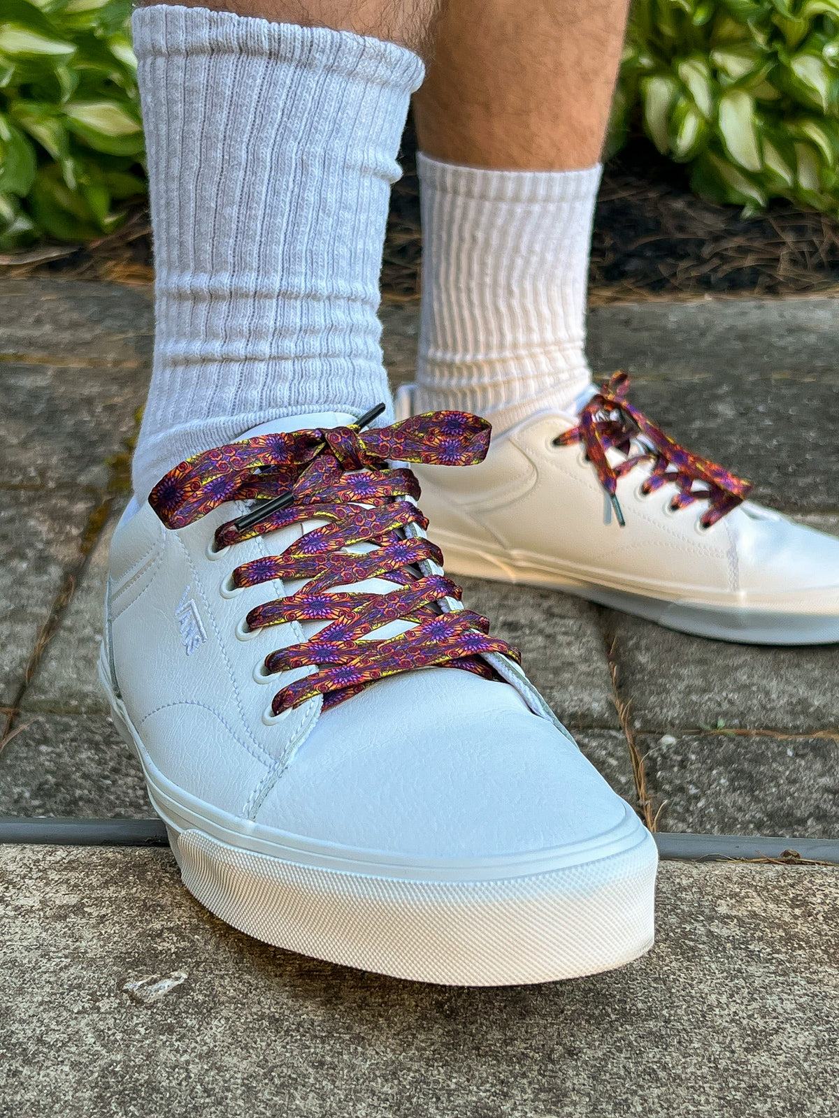 white sneakers with colorful laces worn with white socks on a concrete surface.
