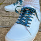 White sneakers with blue and black patterned laces on a concrete surface