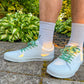 white sneaker with zombie shoelaces worn outdoors on a stone path.