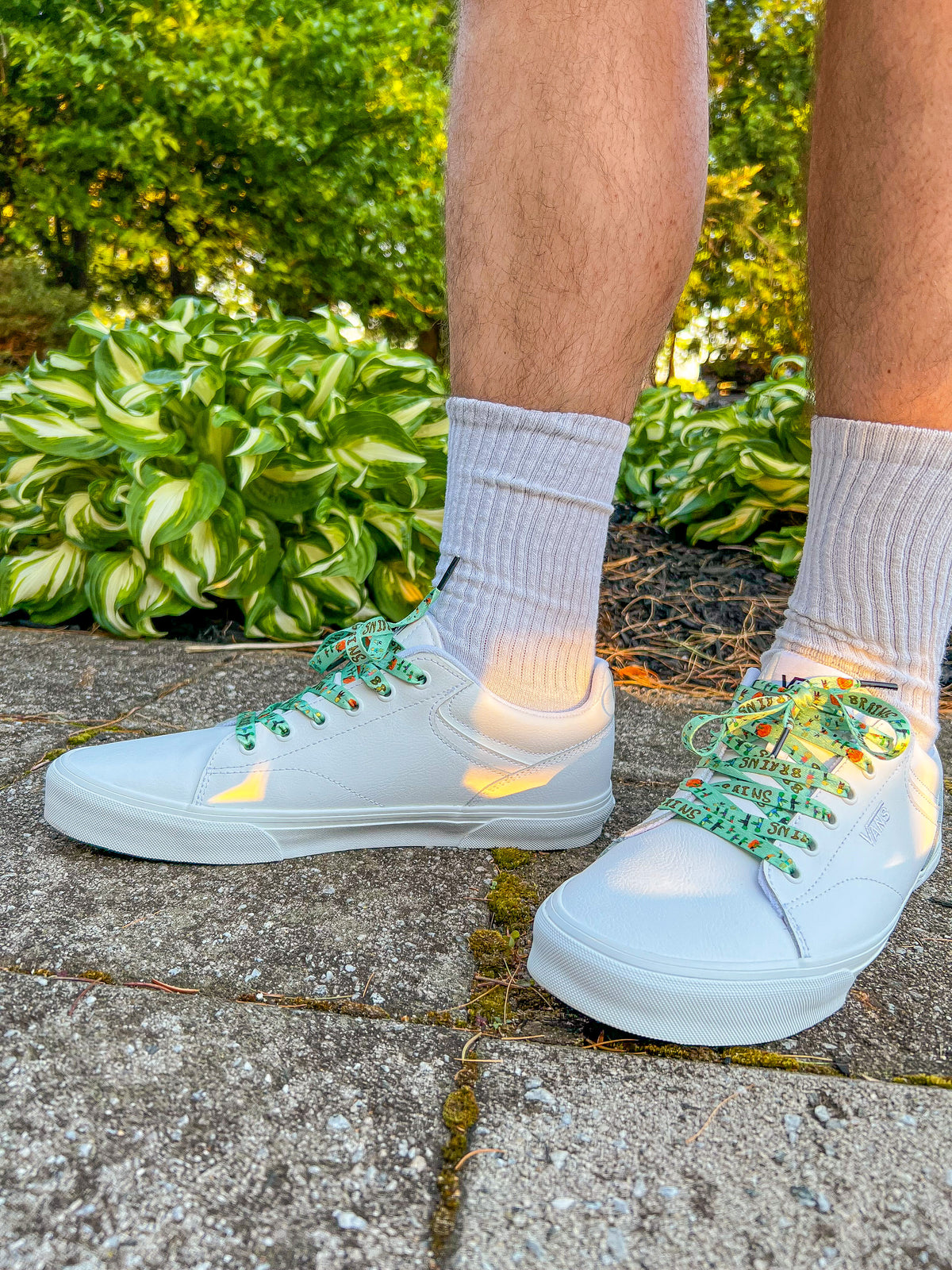 white sneaker with zombie shoelaces worn outdoors on a stone path.