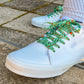 White sneakers with green laces on a concrete surface