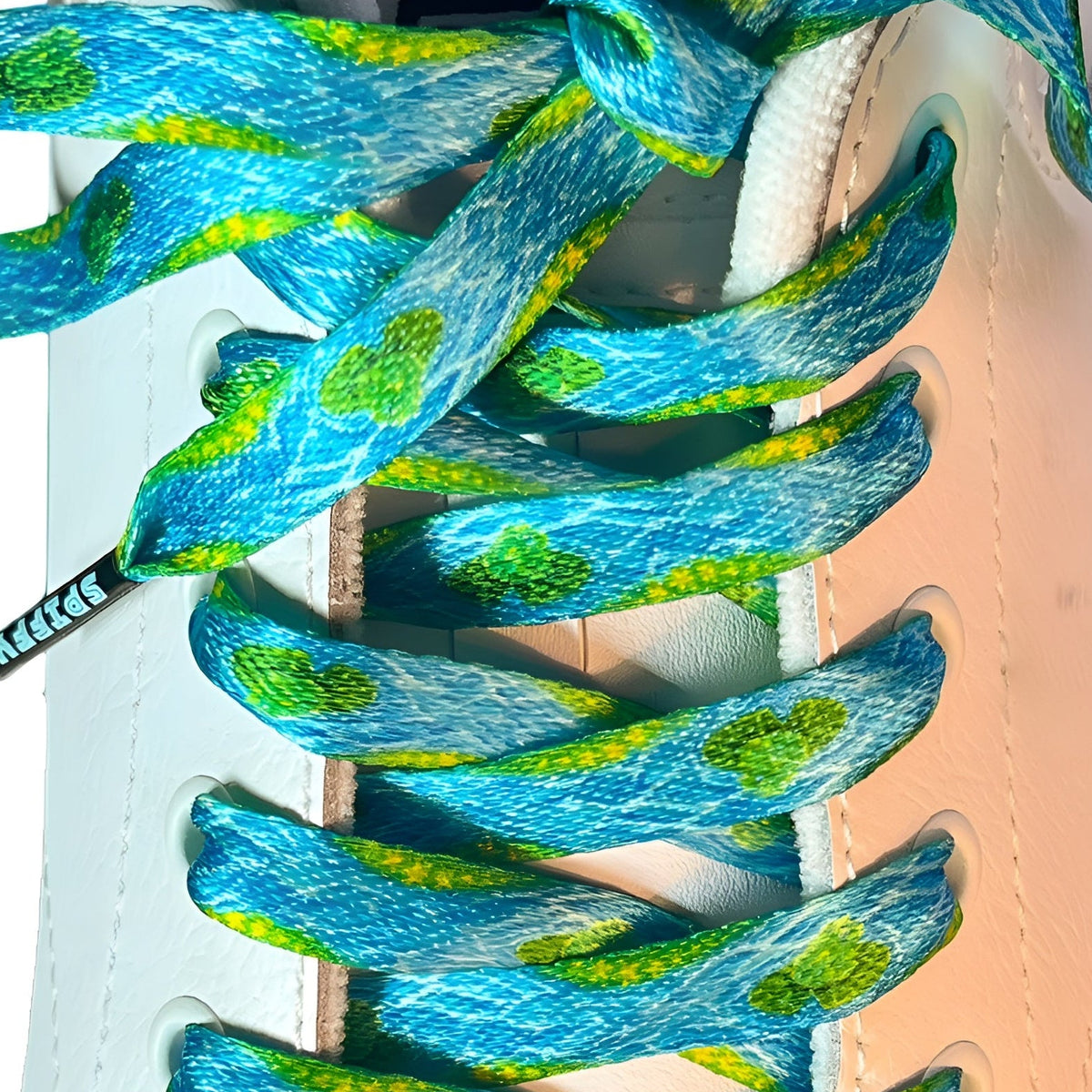 Close-up of blue and green frog shoelaces on a white sneaker with a light pink heel.