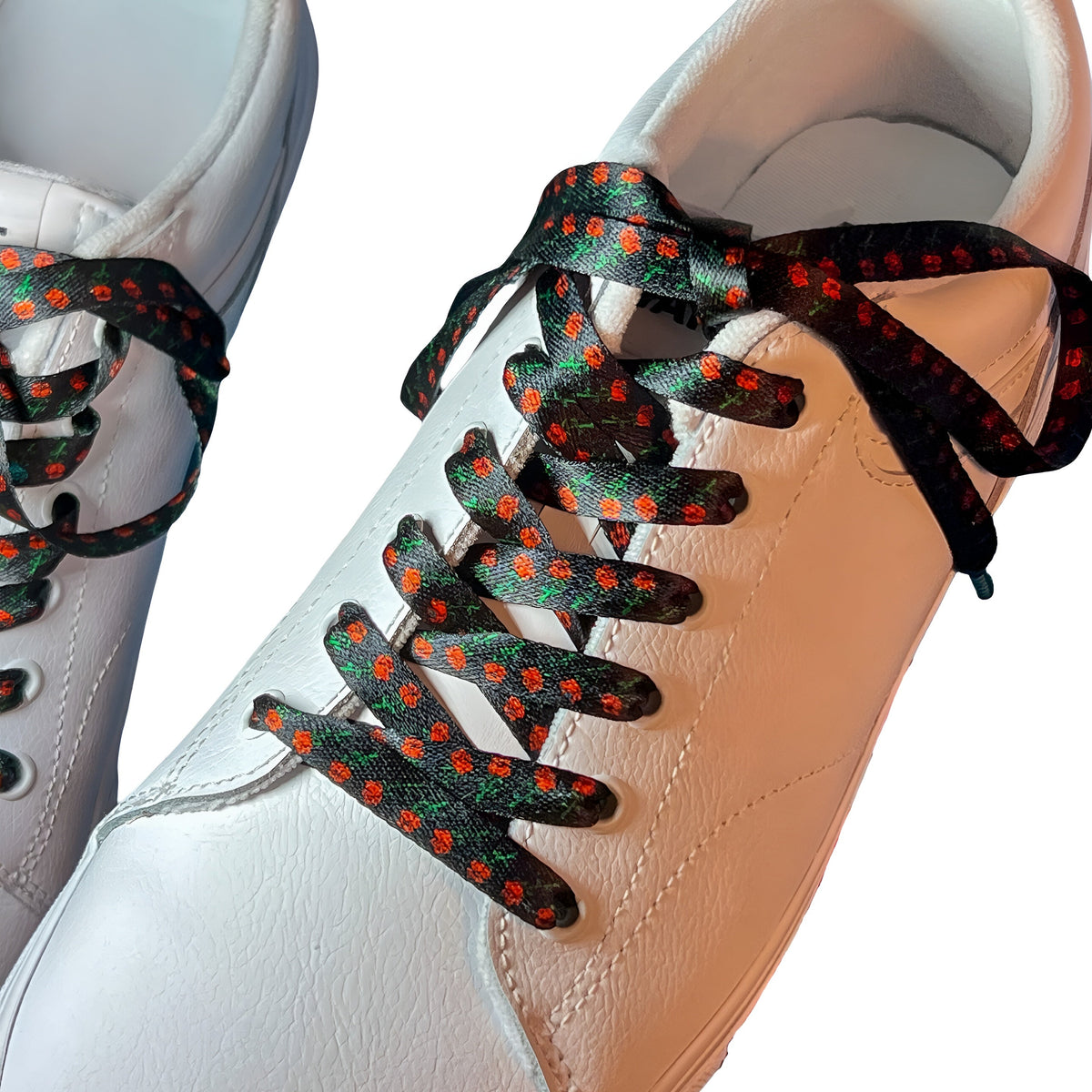 Close-up of a white sneaker with black shoelaces featuring roses on a white background.