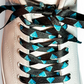 White sneaker with diamond patterned shoelaces on a light gray background
