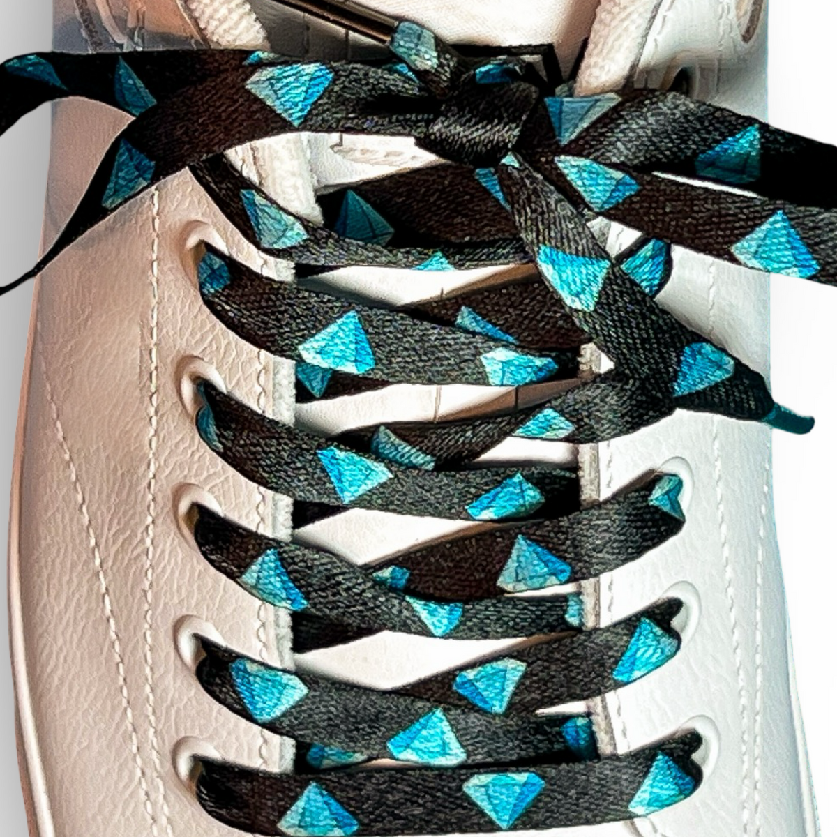 White sneaker with diamond patterned shoelaces on a light gray background