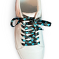 White sneaker with diamond patterned shoelaces on a white background