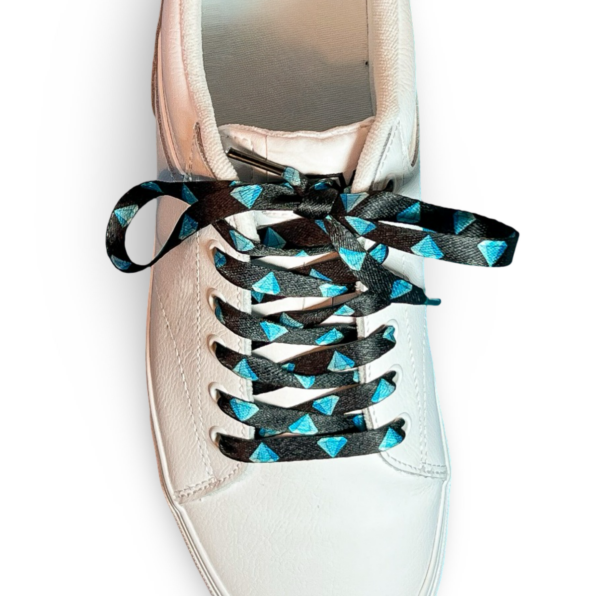 White sneaker with diamond patterned shoelaces on a white background
