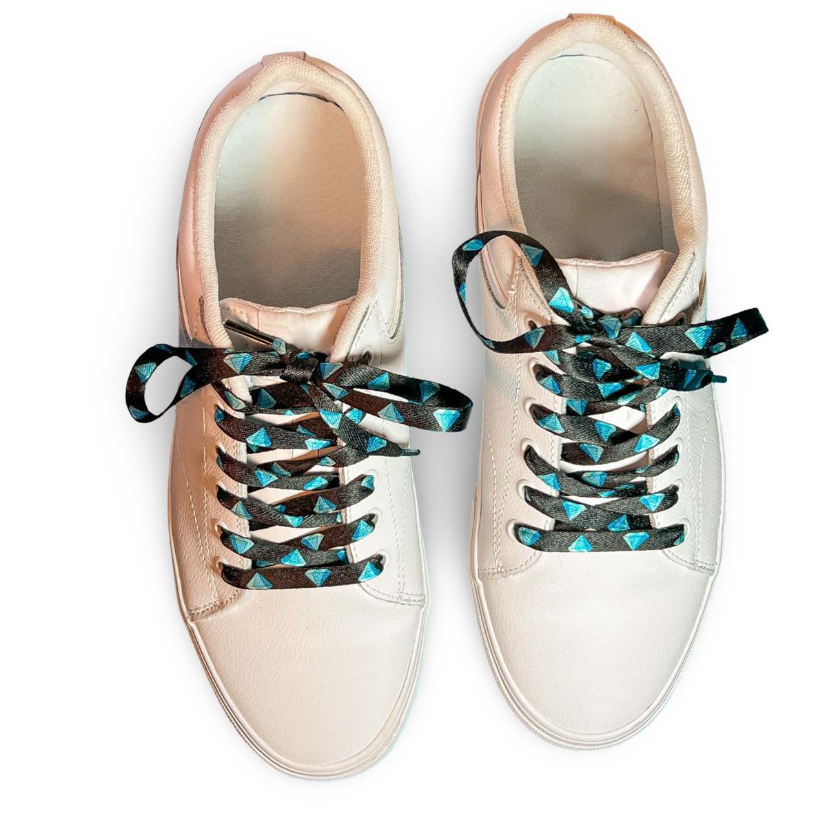 White sneakers with diamond patterned shoelaces on a white background