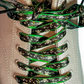 Close-up of green and black patterned shoelaces on a white sneaker.
