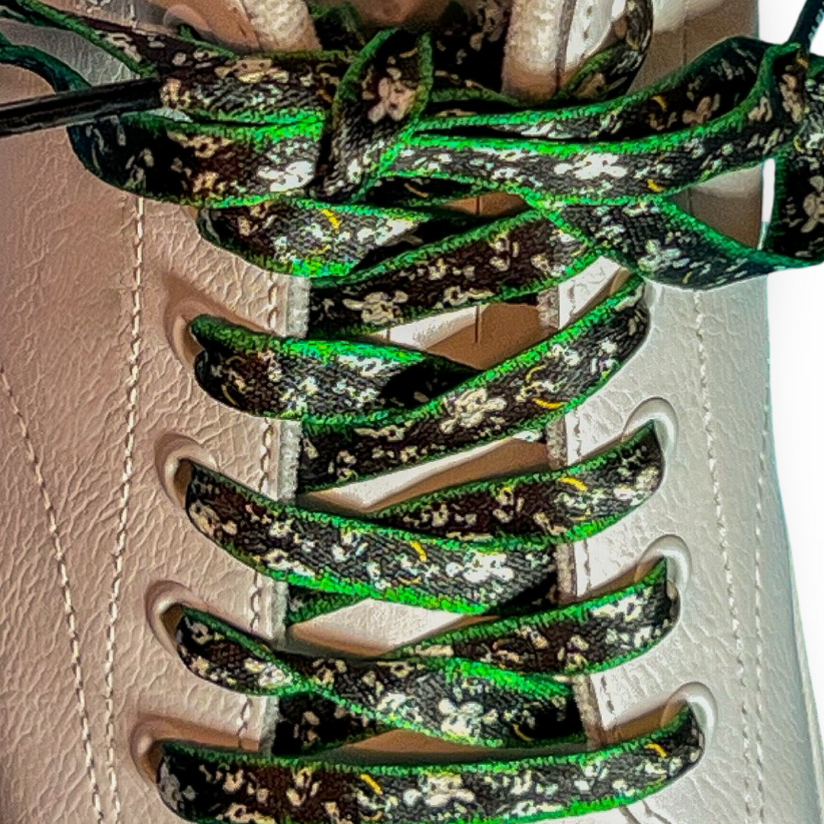 Close-up of green and black patterned shoelaces on a white sneaker.