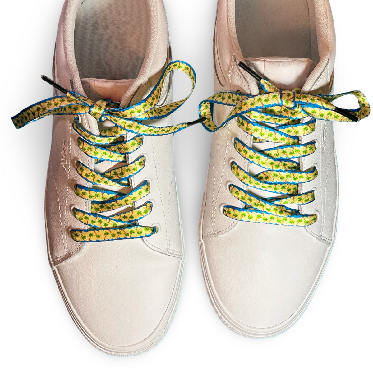 Pair of beige sneakers with colorful palm tree shoelaces on a white background