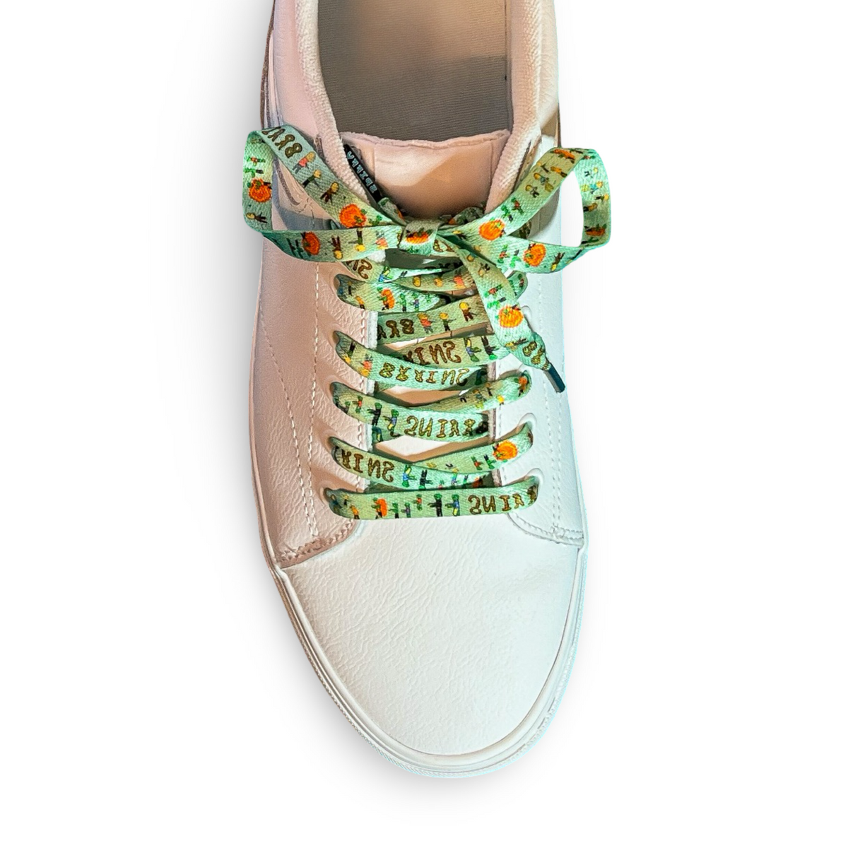 White sneaker with green patterned laces on a white background