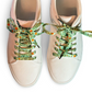 Beige sneakers with green patterned laces on a white background