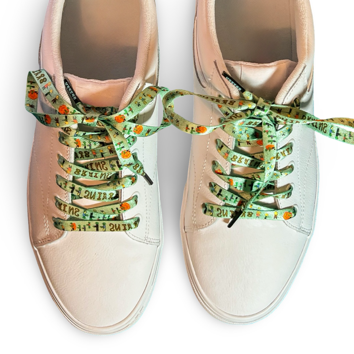 Beige sneakers with green patterned laces on a white background