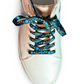 Shiny pink sneaker with evil eye themed shoelaces on a white background