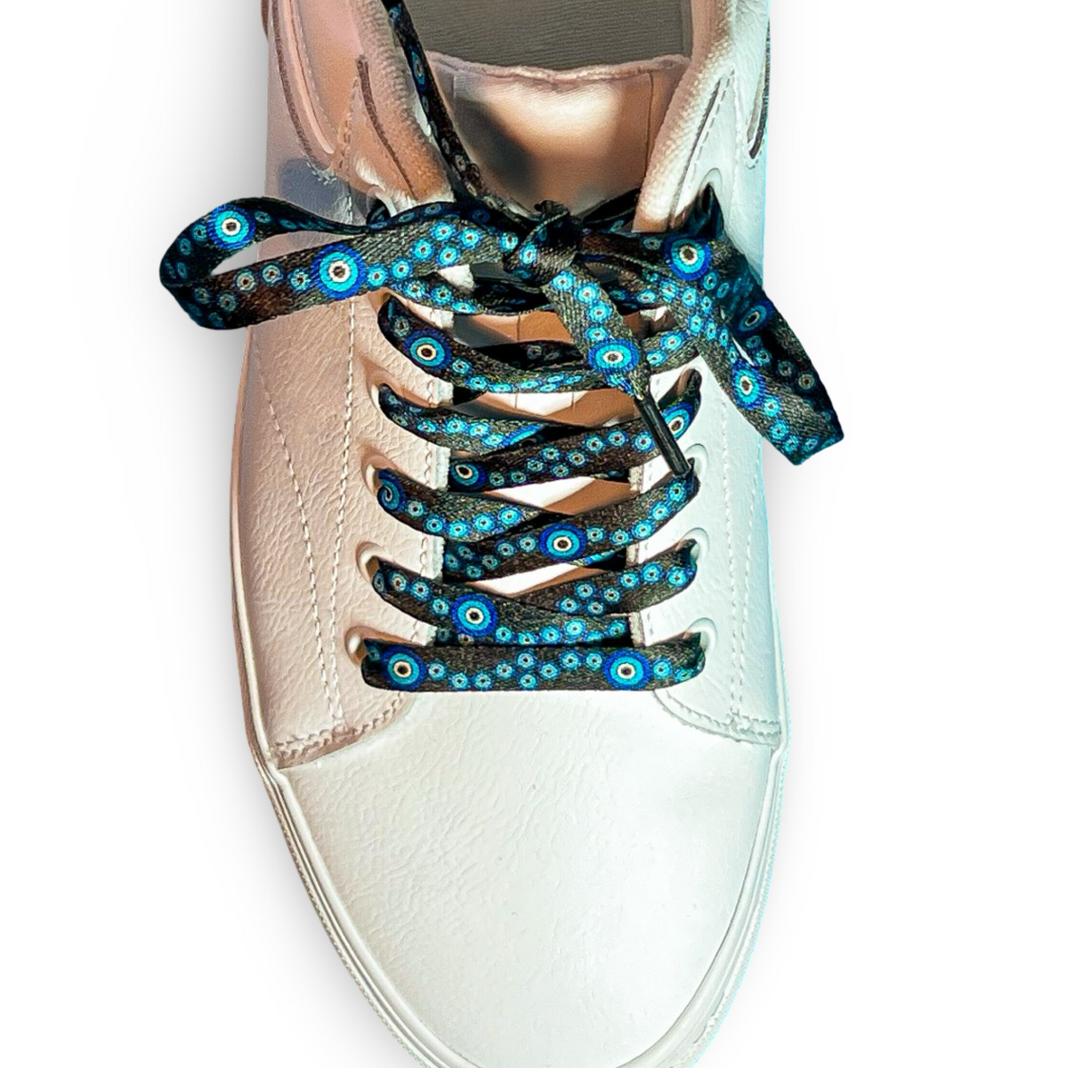 Shiny pink sneaker with evil eye themed shoelaces on a white background