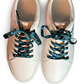 Pair of white sneakers with evil eye themed shoelaces on a white background