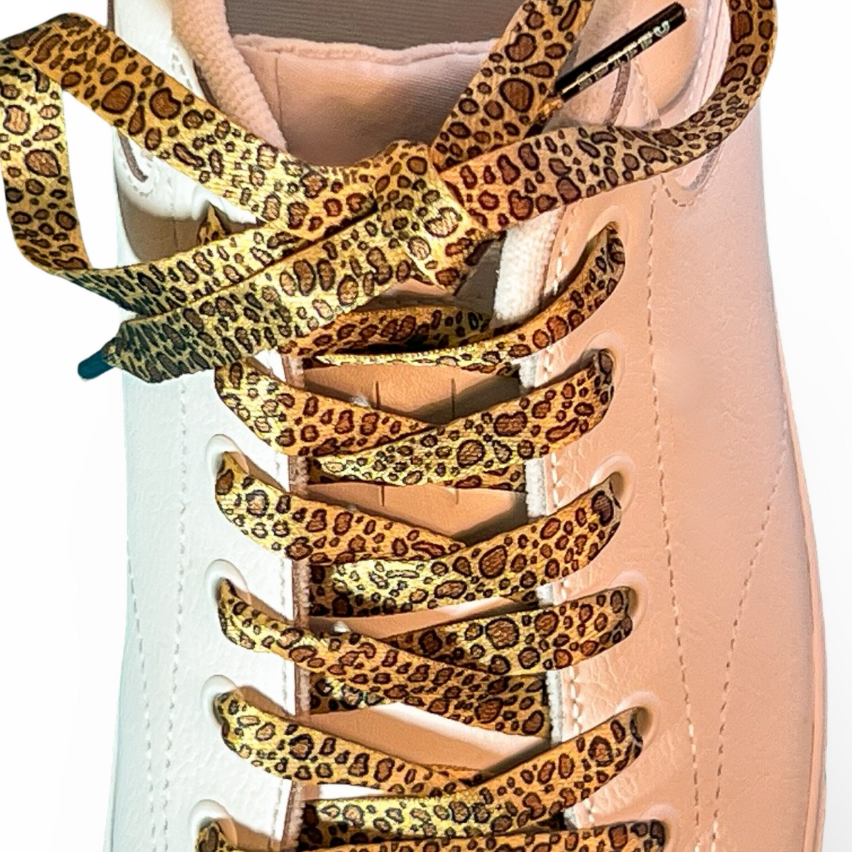 Leopard print shoelaces on a light pink sneaker with a white background