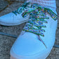 White sneakers with colorful butterfly themed laces on a concrete surface