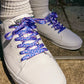 White sneakers with blueberry patterned laces on a concrete surface