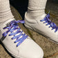 White sneakers with blue patterned laces on a concrete surface