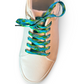 Beige sneaker with blue and green patterned laces on a white background