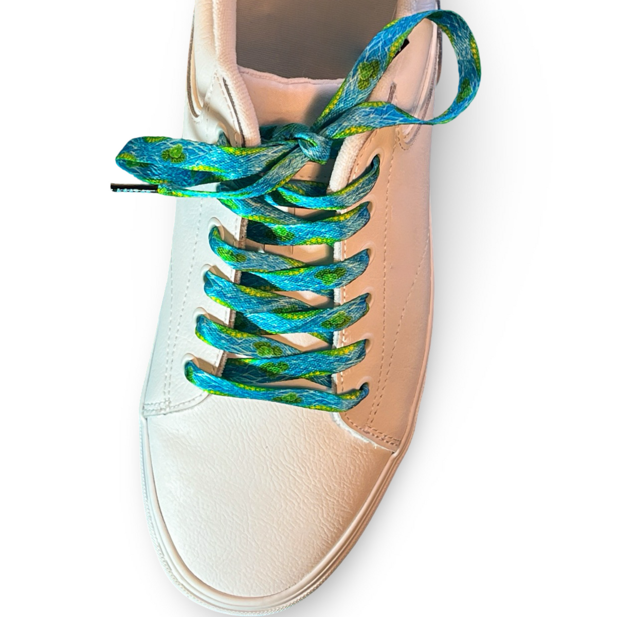 Beige sneaker with blue and green patterned laces on a white background