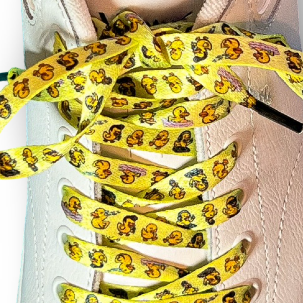 Yellow shoelaces with rubber ducks tied on a white sneaker