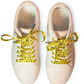 Beige sneakers with yellow duck themed shoelaces on a white background
