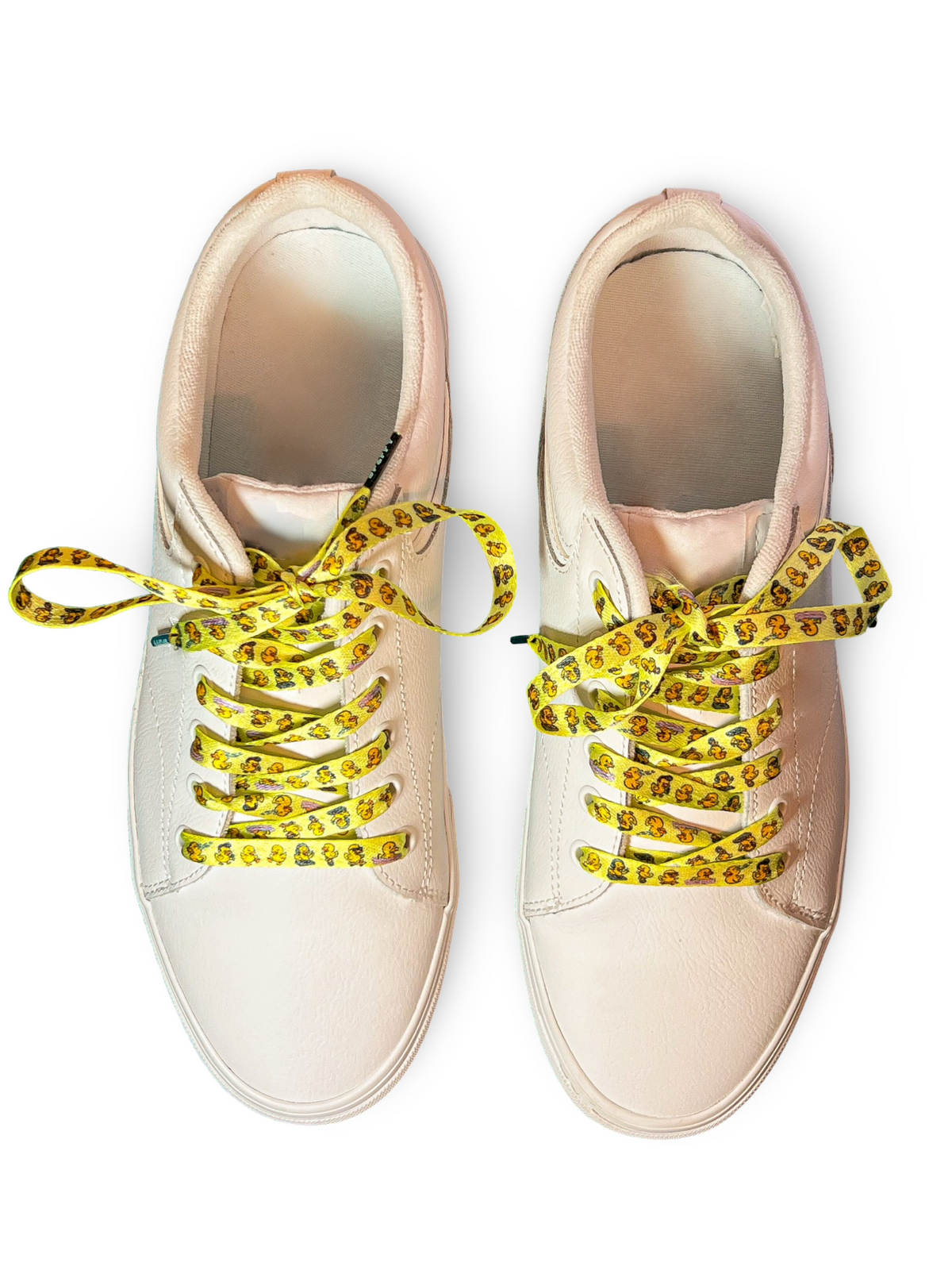 Beige sneakers with yellow duck themed shoelaces on a white background