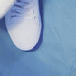 Green and yellow pickle patterned shoelaces being laced up on a fresh pair of white sneakers