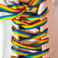 Close-up of rainbow-colored shoelaces on a white sneaker.