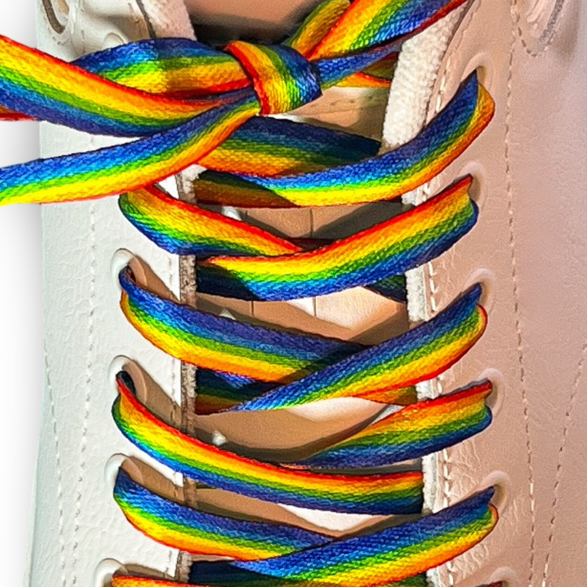 Close-up of rainbow-colored shoelaces on a white sneaker.