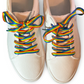 Beige sneakers with rainbow laces on a white background